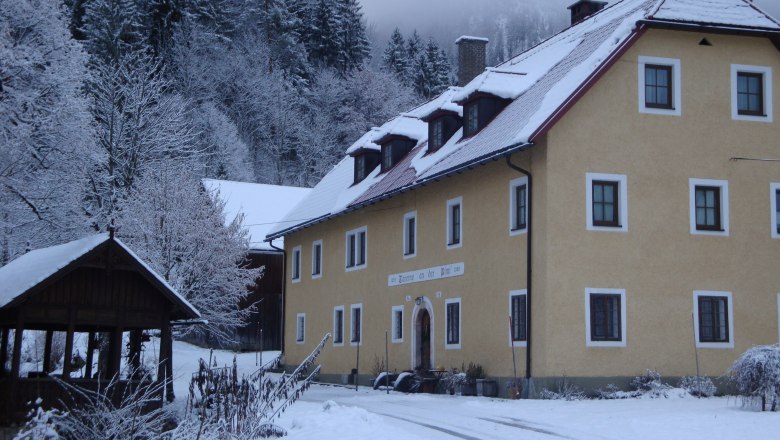 Rinntaverne, © Rinntaverne A yellow building in the snow, surrounded by snow-covered trees and a wooden pavilion.