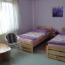 A simply furnished room with two single beds, a small table and two chairs.