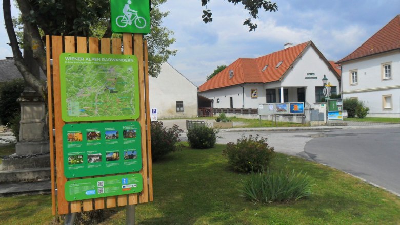 Cycle starting point board in Walpersbach with map and information, surrounded by buildings and trees.