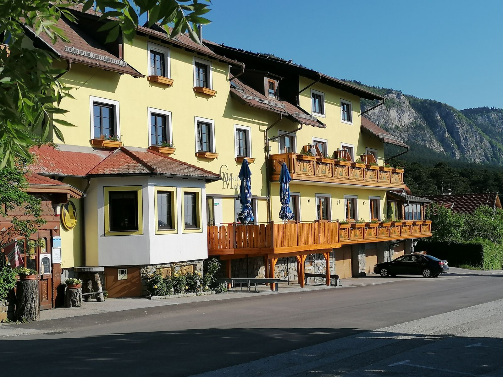 Yellow inn with wooden balconies and a mountain in the background.