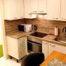 Modern kitchen with wooden worktop, white cupboards, microwave, stove and sink.