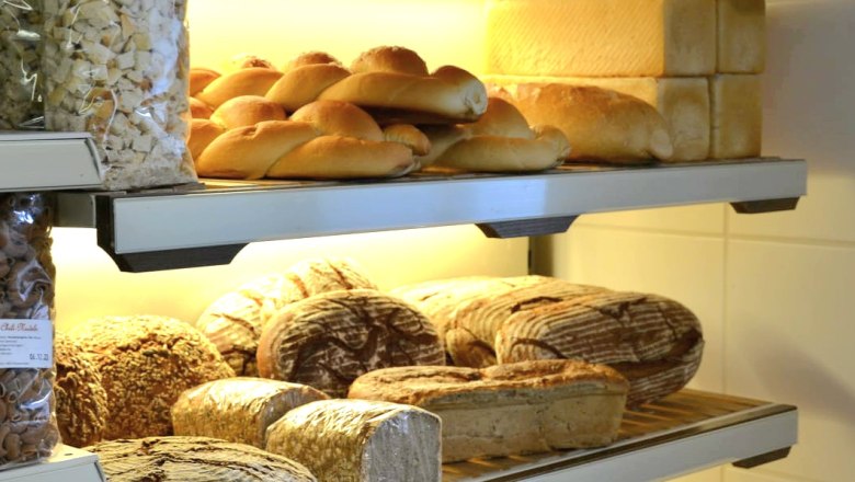 Shelves with different types of bread and pastries in a bakery.