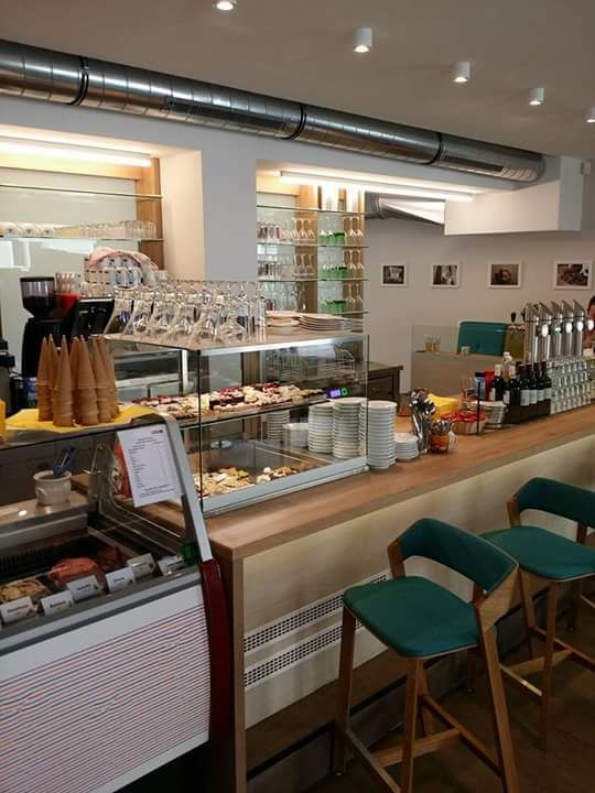 Interior view of a café with counter, bar stools and a display case with snacks.