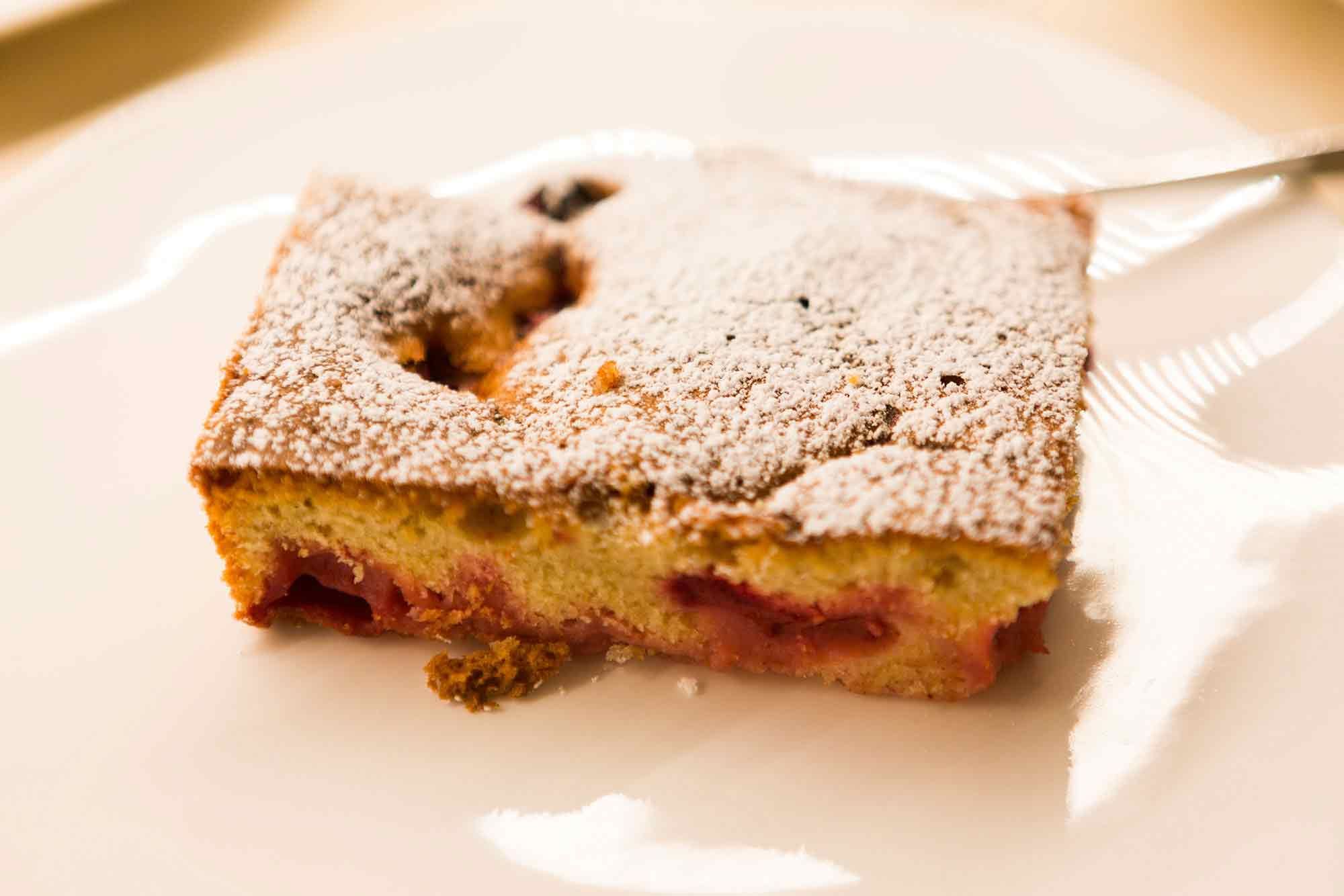 A slice of homemade cake dusted with powdered sugar on a plate.