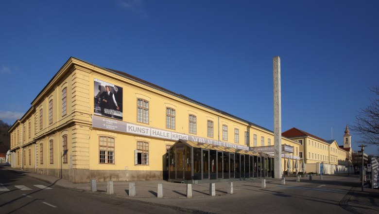 Exterior view of the Kunsthalle Krems, a yellow building with large windows and a poster on the fa&ccedil;ade.