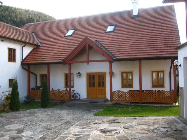 A traditional building with a red tiled roof and wooden elements, surrounded by a paved courtyard.