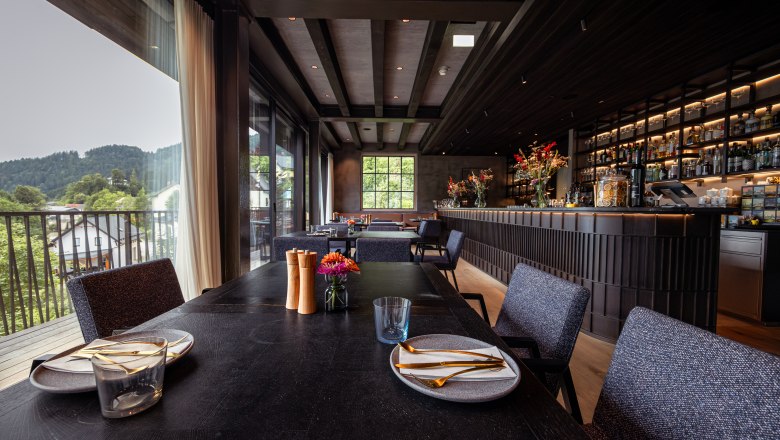 Interior view of a modern restaurant with a set table and bar in the background.