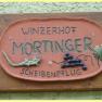 Sign with the inscription 'Winzerhof Mörtinger Scheibenpflug' and decorations of grapes and a lizard.