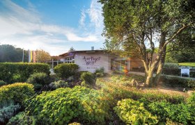 Entrance to Amethyst Welt Maissau with garden and trees in the foreground.