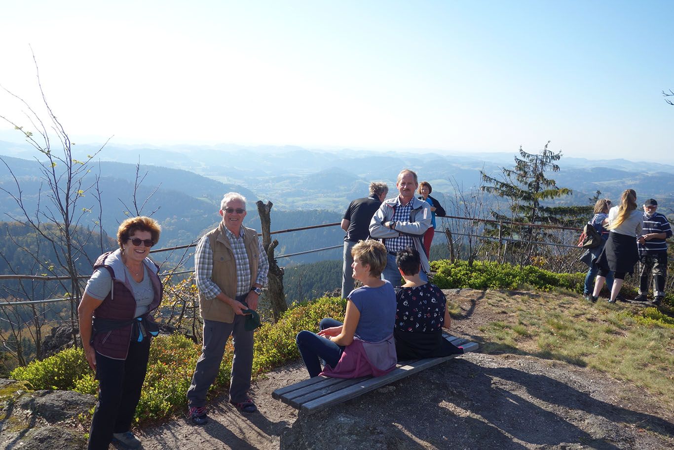 People enjoy the view from a mountain top with a wide view over the landscape.