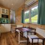 Small kitchen with dining area and window with view of meadow and forest.