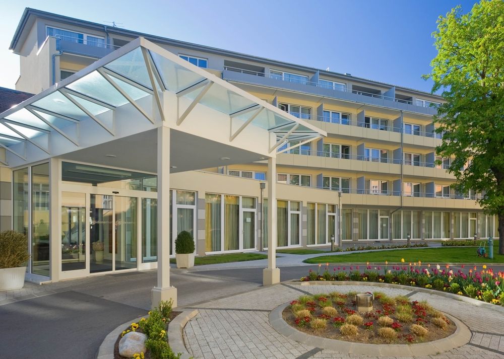 Modern building entrance with glass roof and garden.