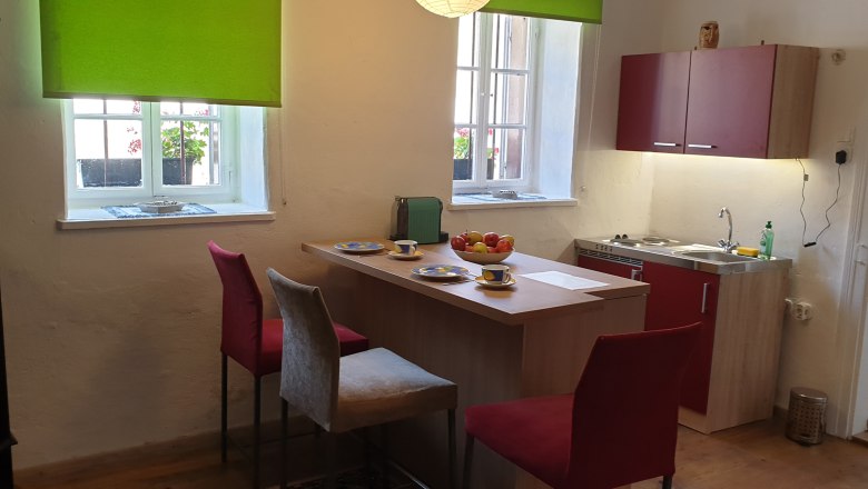 Kitchen with dining table, chairs and window with green blind.