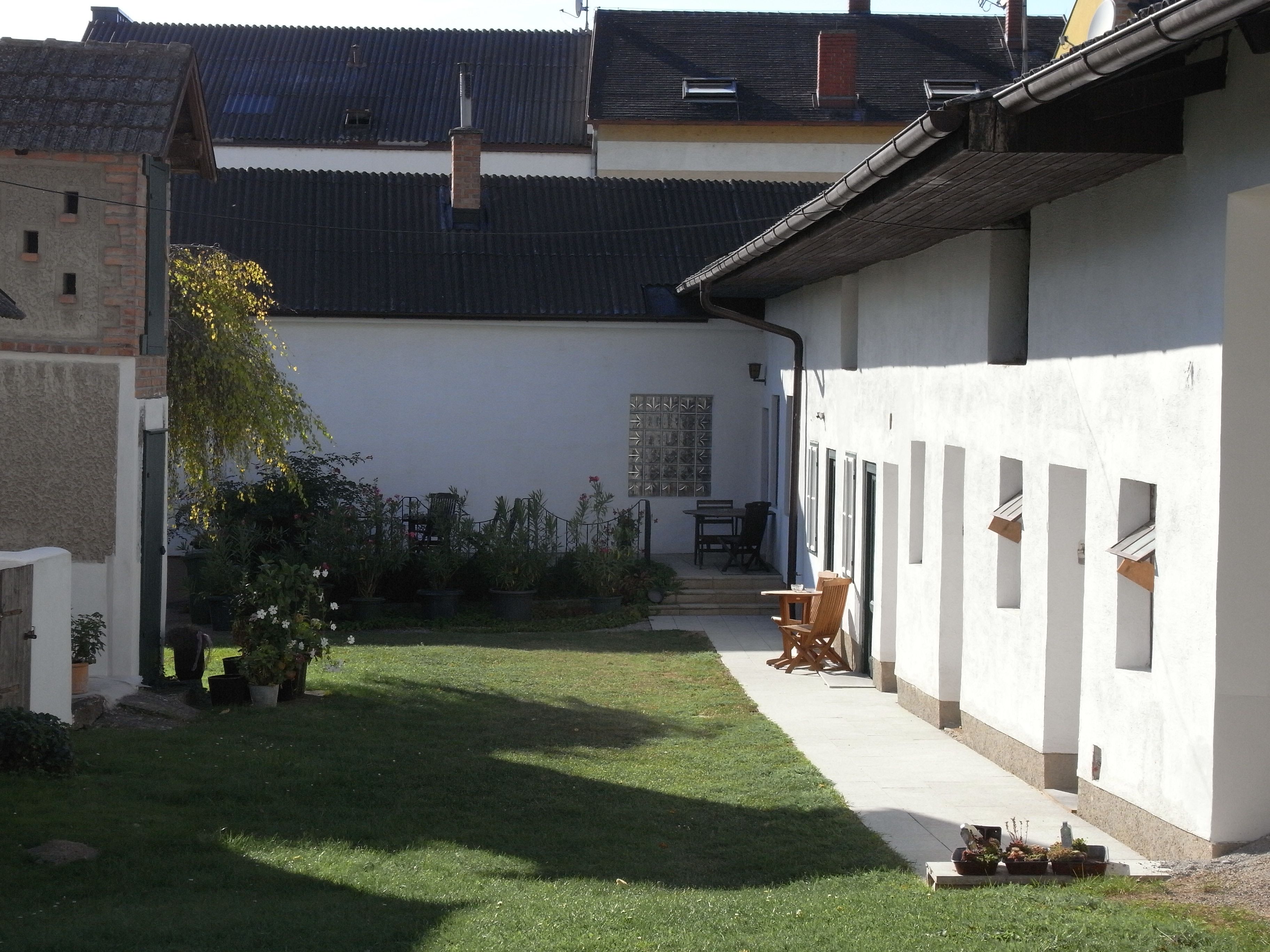 Courtyard with lawn, white buildings and garden furniture.