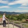 Man standing on terrace with view of village and hills.