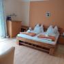 Cozy bedroom with double bed, wooden furniture and orange wall.