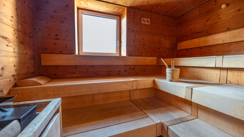 Interior view of a wooden sauna with window and sauna bucket.