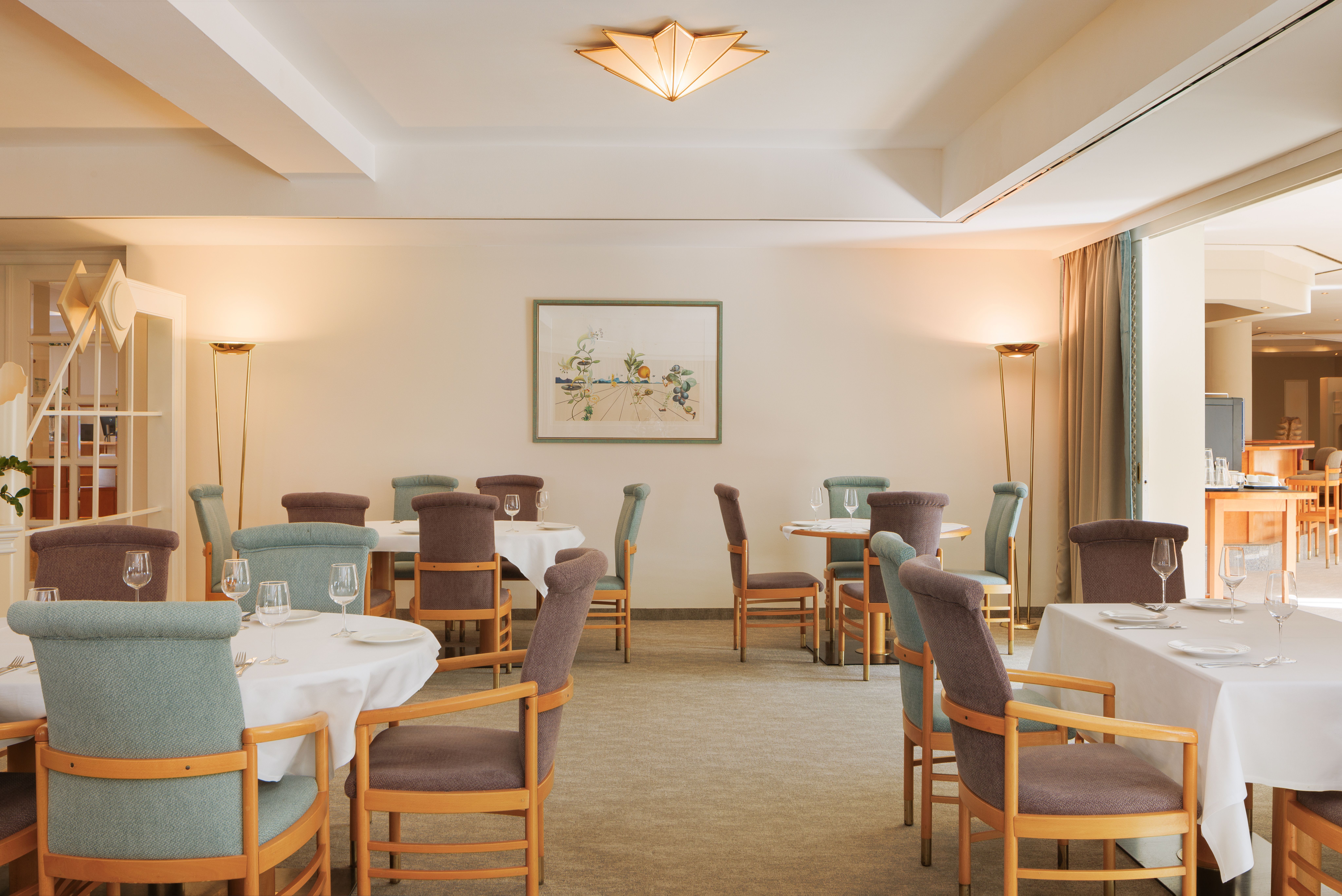 Elegant restaurant with laid tables and upholstered chairs.