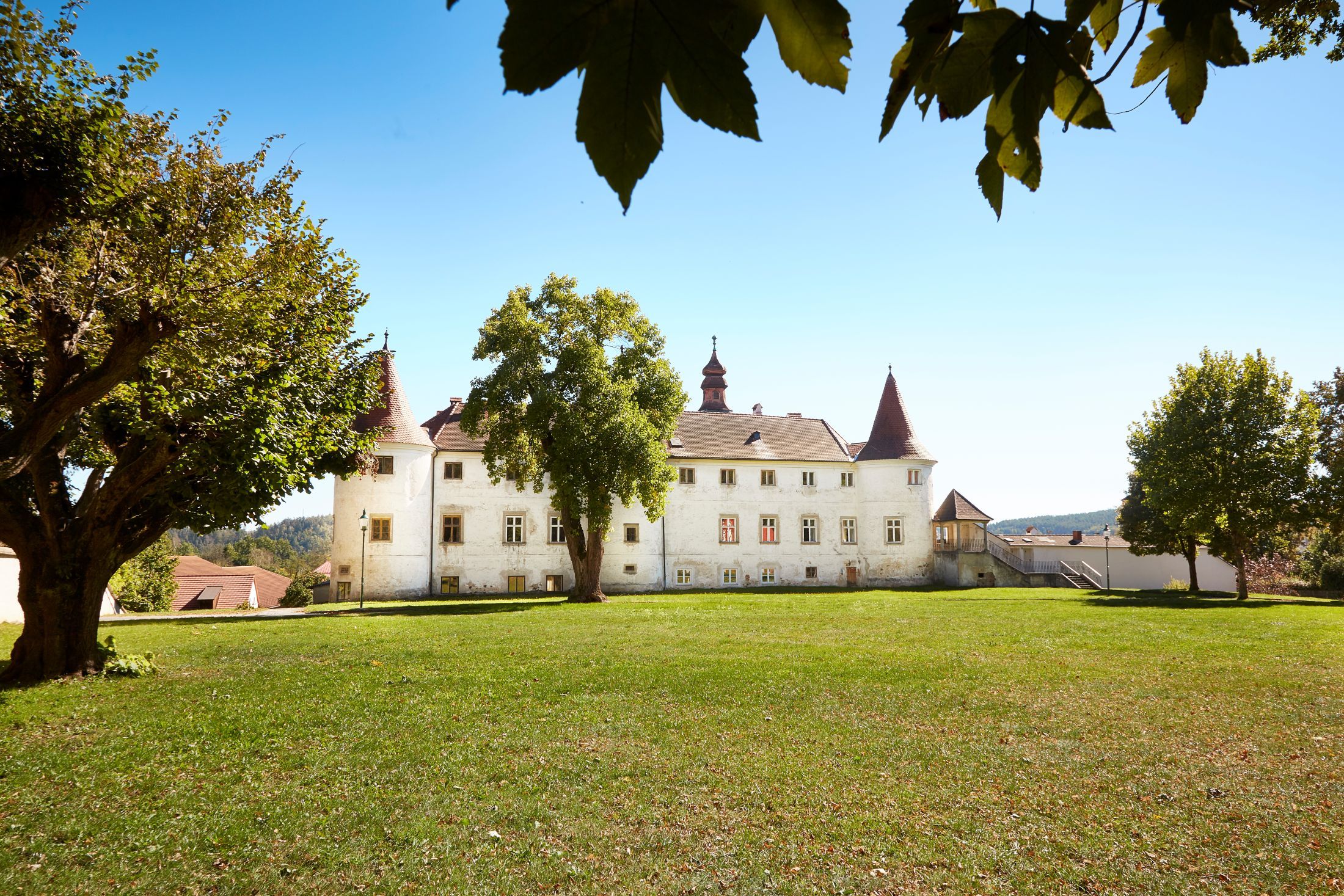 Dobersberg Castle with a green meadow in the foreground and trees in the background.