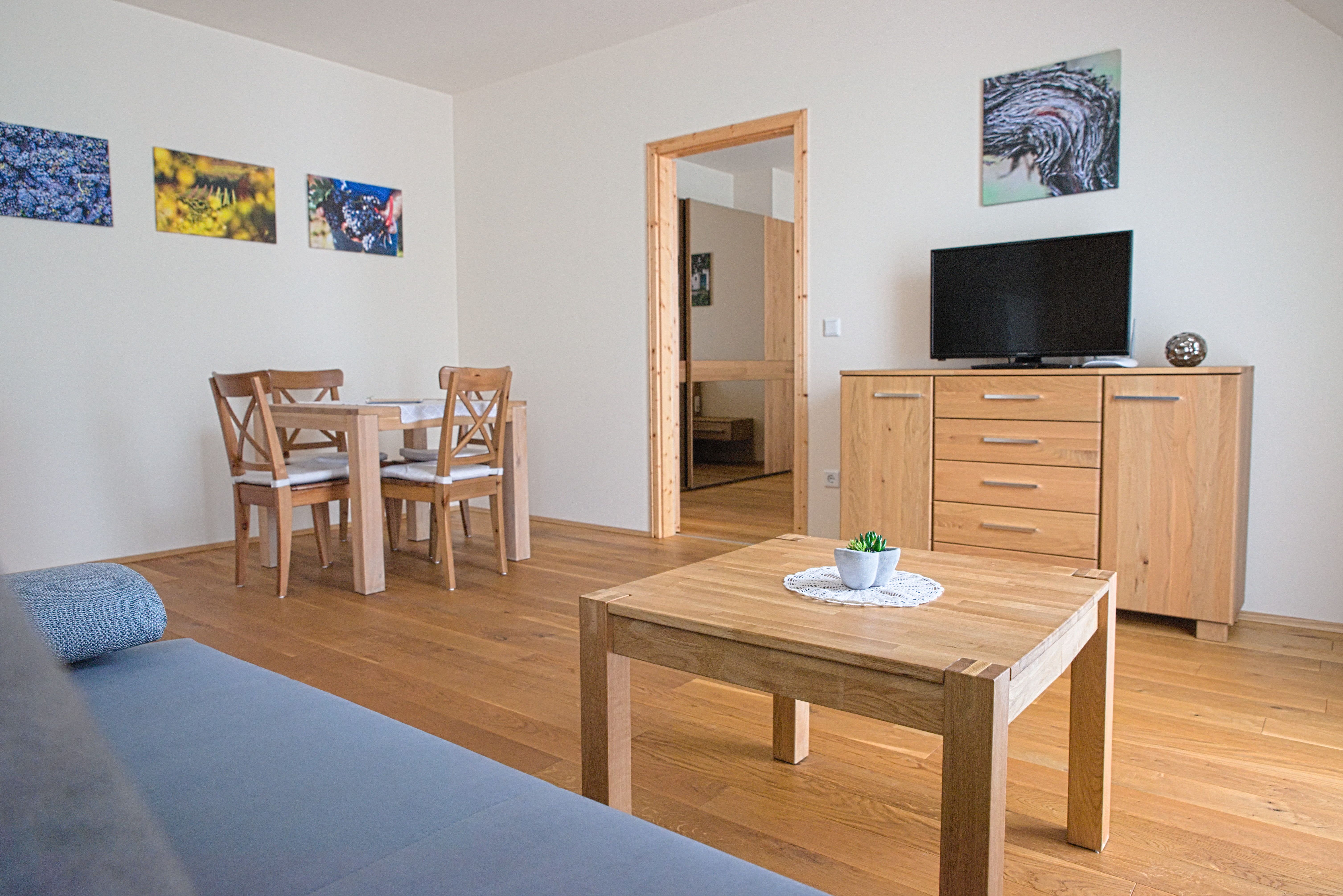 A modern guest room with wooden furniture, a table, chairs, a TV and murals.