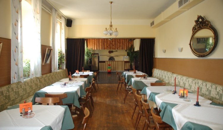 A traditional inn with wooden floors, laid tables and a chandelier.