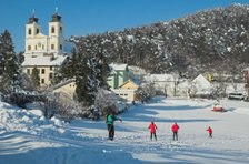 Winter landscape with church and cross-country skiers.
