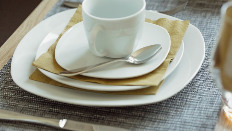 Table set with white crockery, cup and cutlery.
