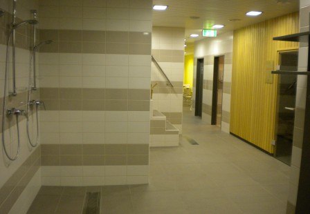 Interior view of a sauna area with showers and wooden walls.