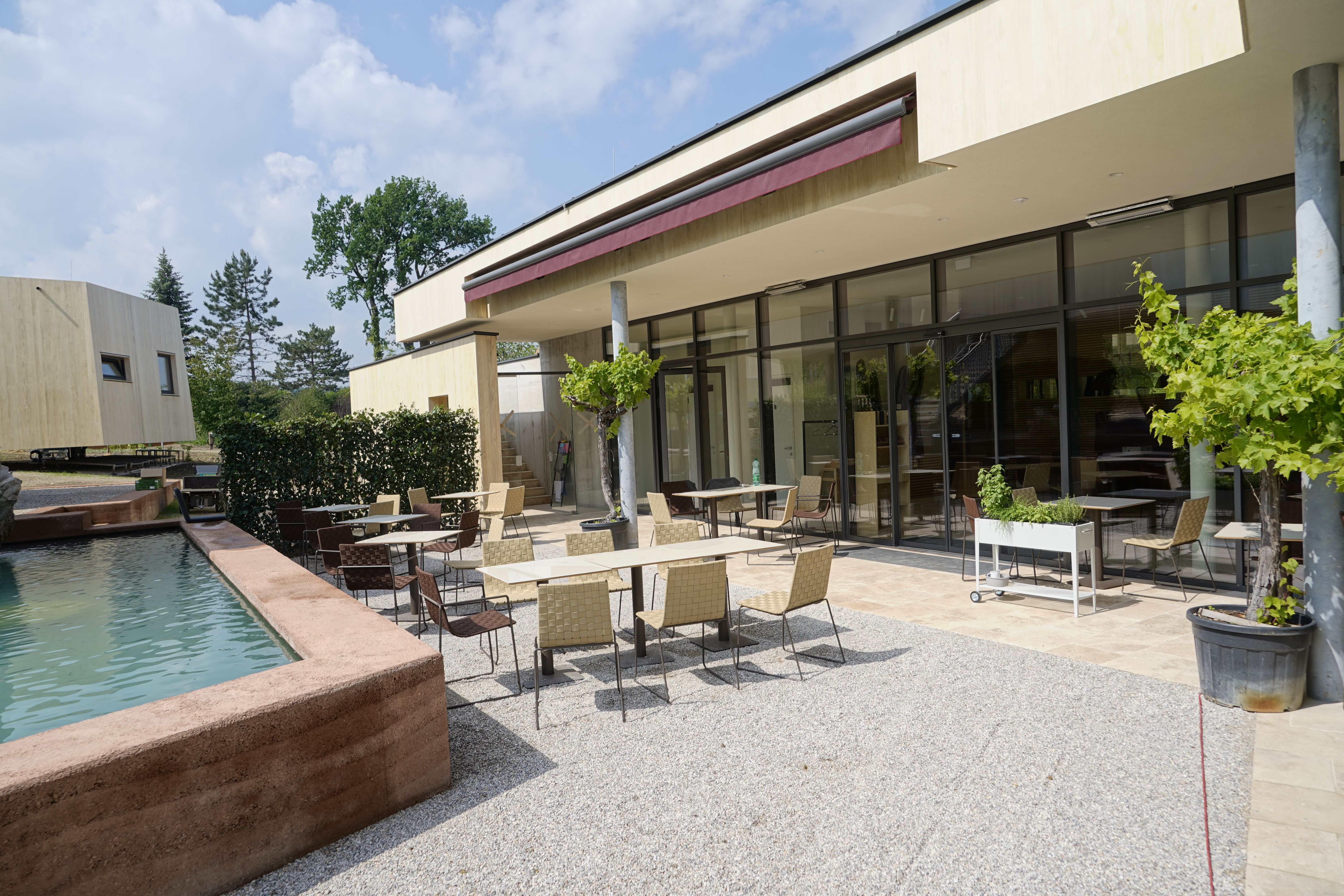 Outdoor area of a modern breakfast restaurant with tables and chairs on a terrace next to a water basin.