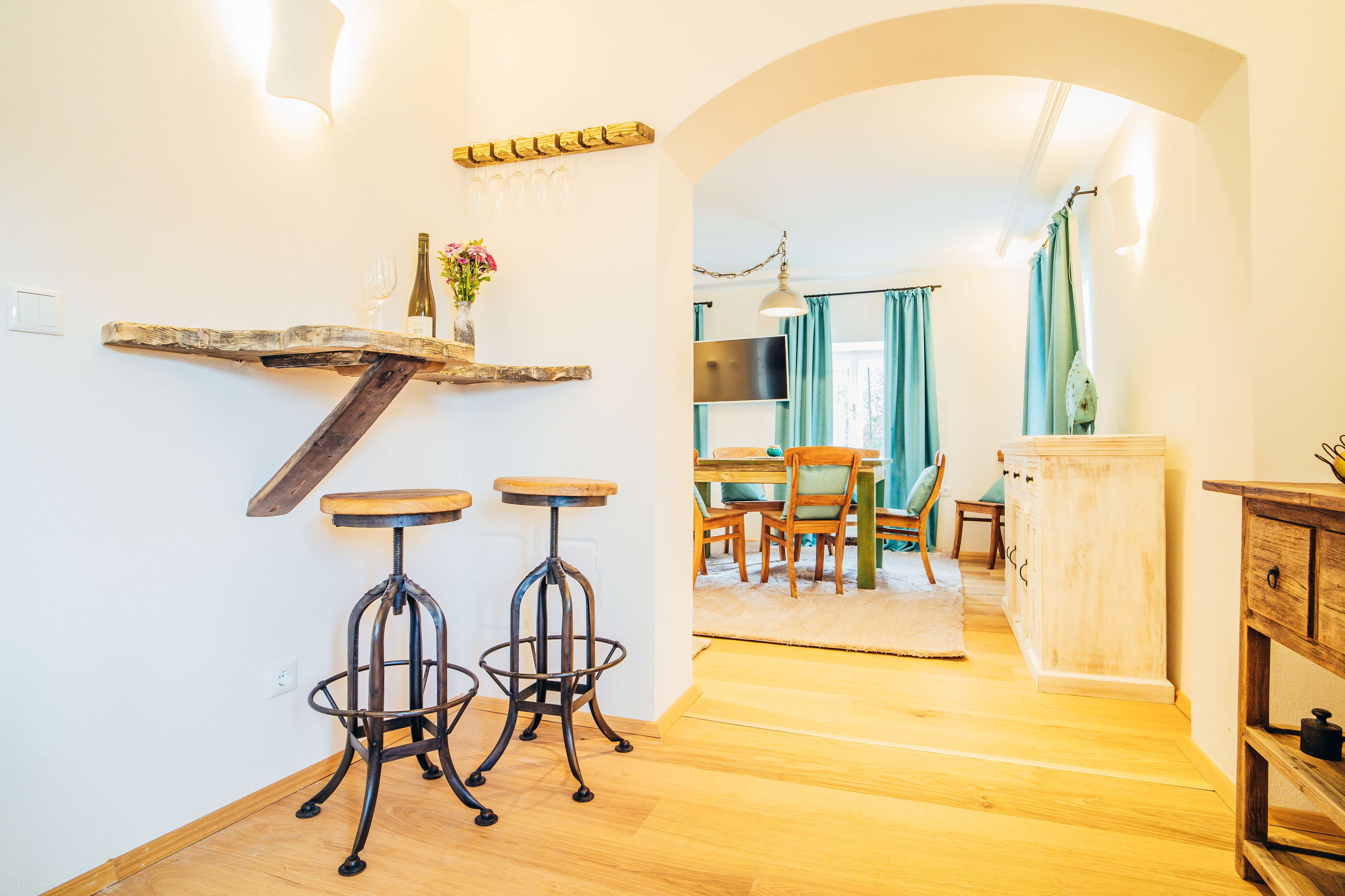 Cozy living room with wooden furniture, bar stools and dining table.