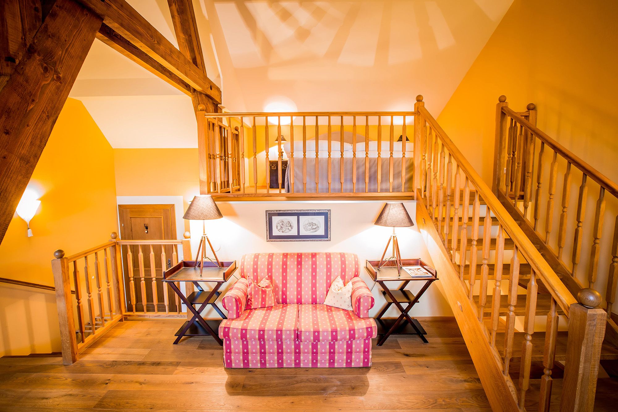 Cozy suite with wooden beams, staircase, sofa and lamps.