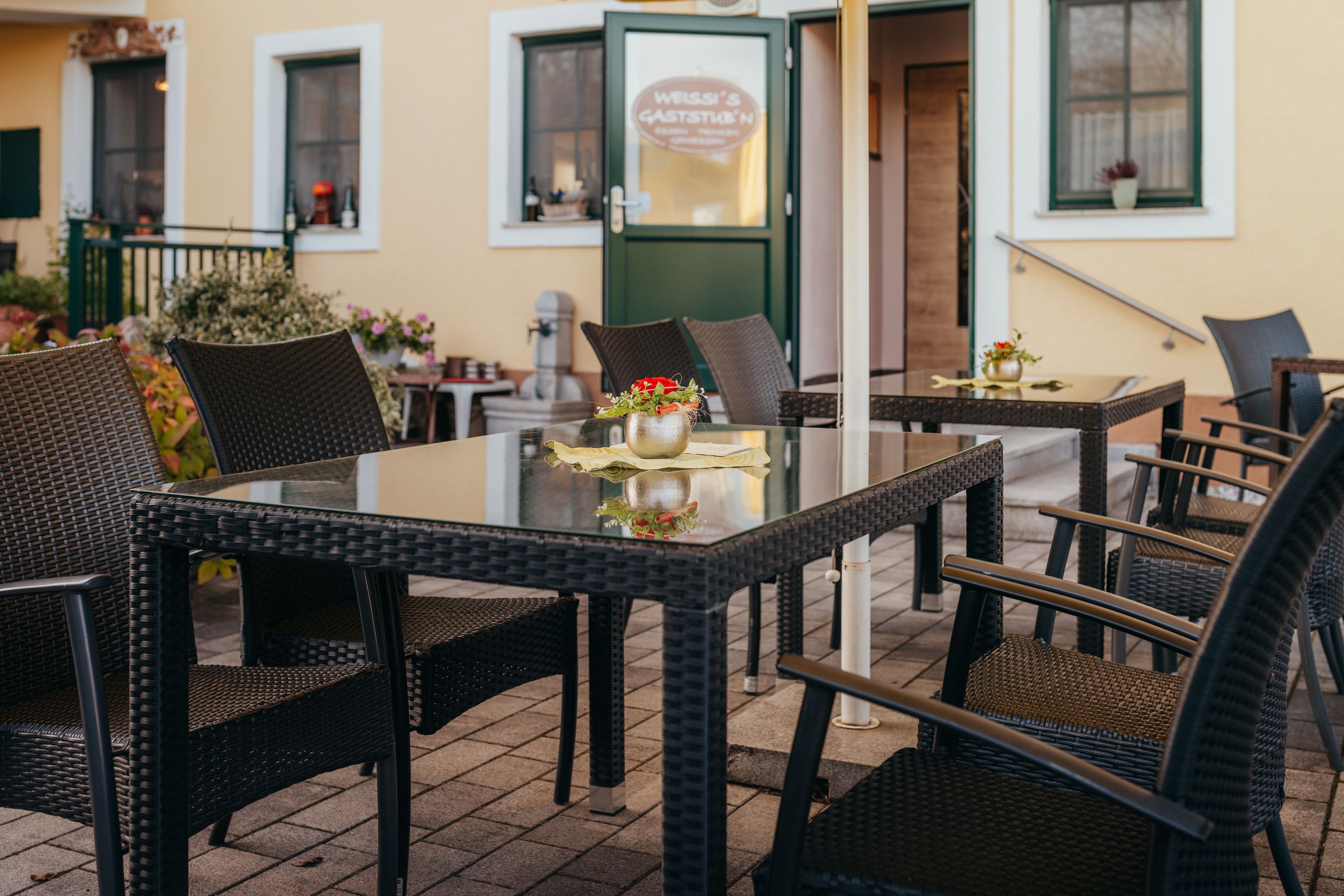 Cozy outdoor area of an inn with rattan furniture and flowers.
