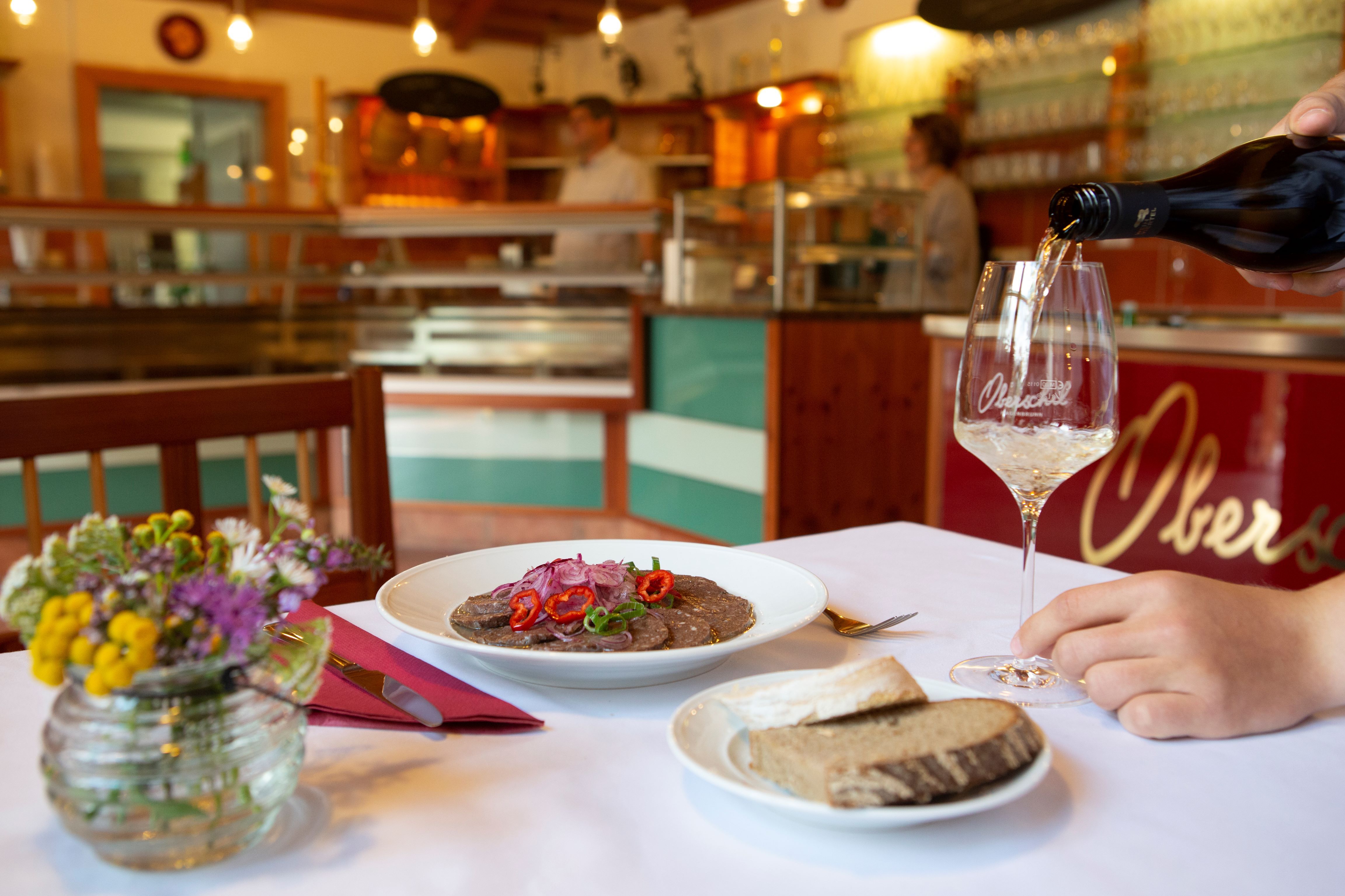 A laid table in a wine tavern with a plate of food, bread and a glass of wine.
