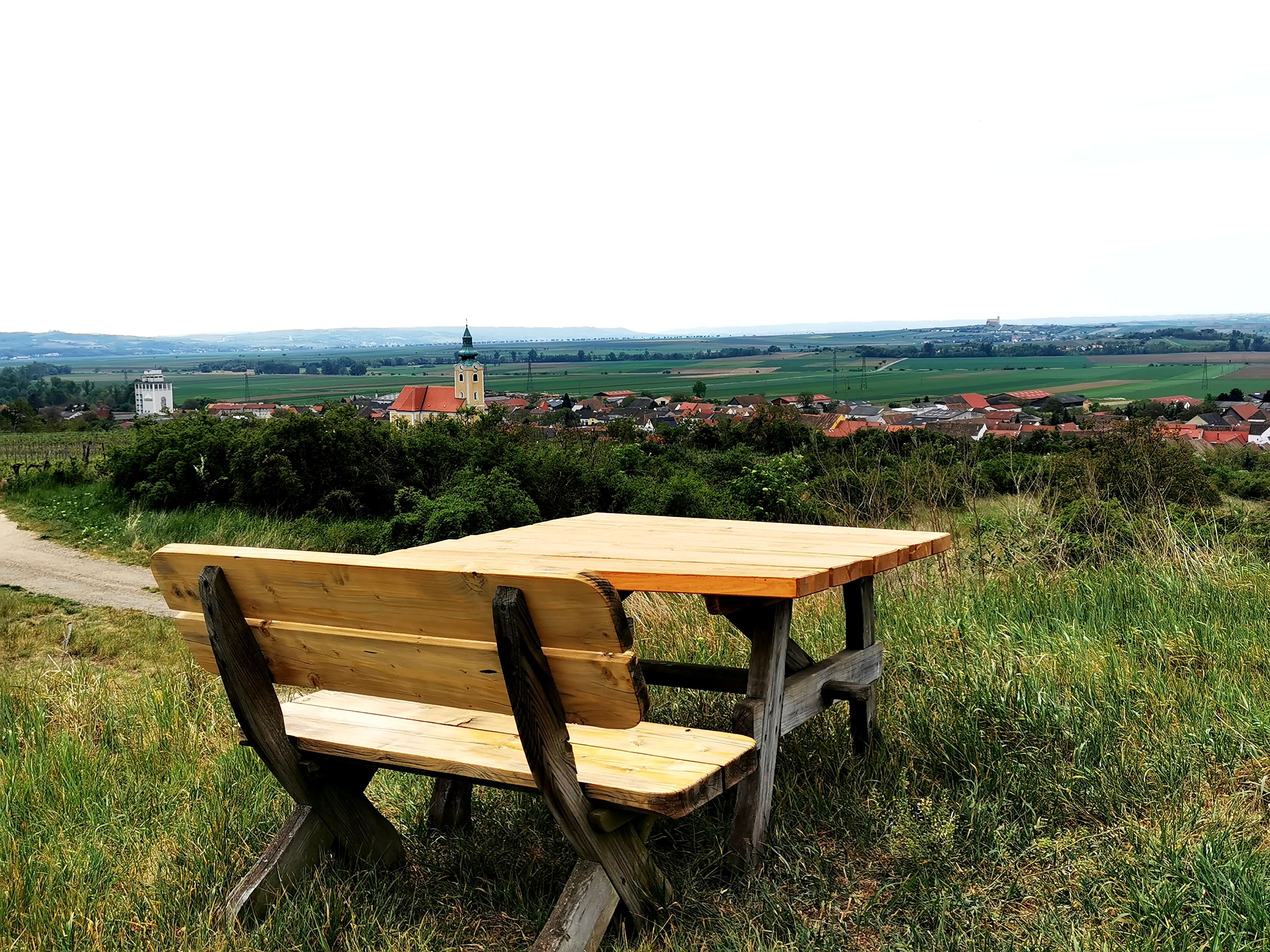 Wooden bench with table on a hill with a view of Röschitz and the surrounding countryside.