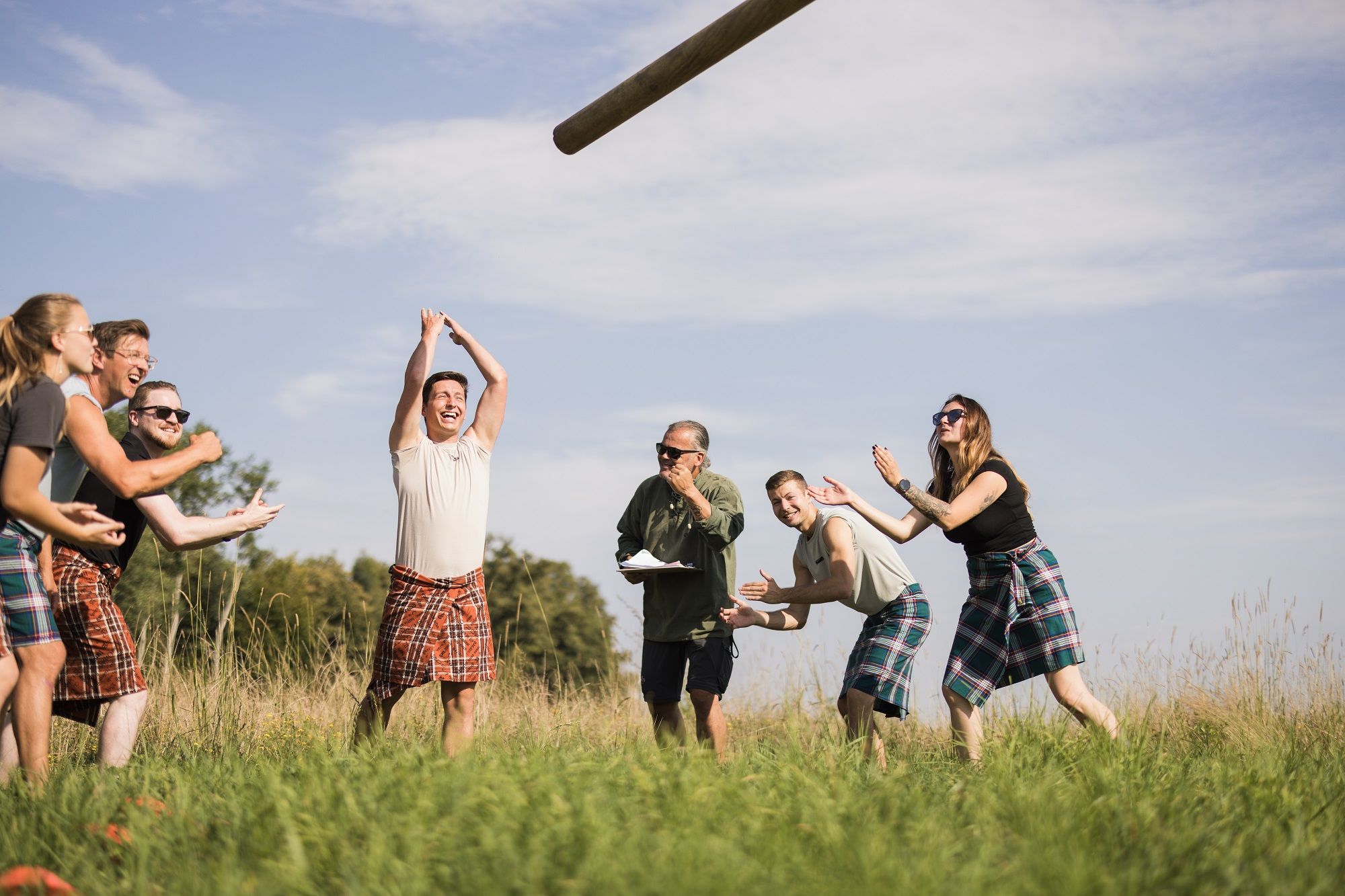 Group of people in kilts at the Highland Games on a meadow.