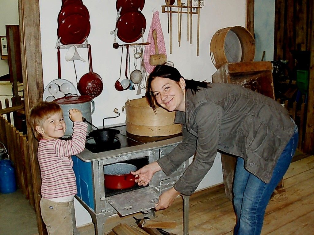 A woman and a child play in a historic kitchen with old kitchen utensils.