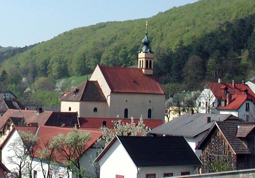 Maria Raisenmarkt pilgrimage church in a rural setting with hills in the background.