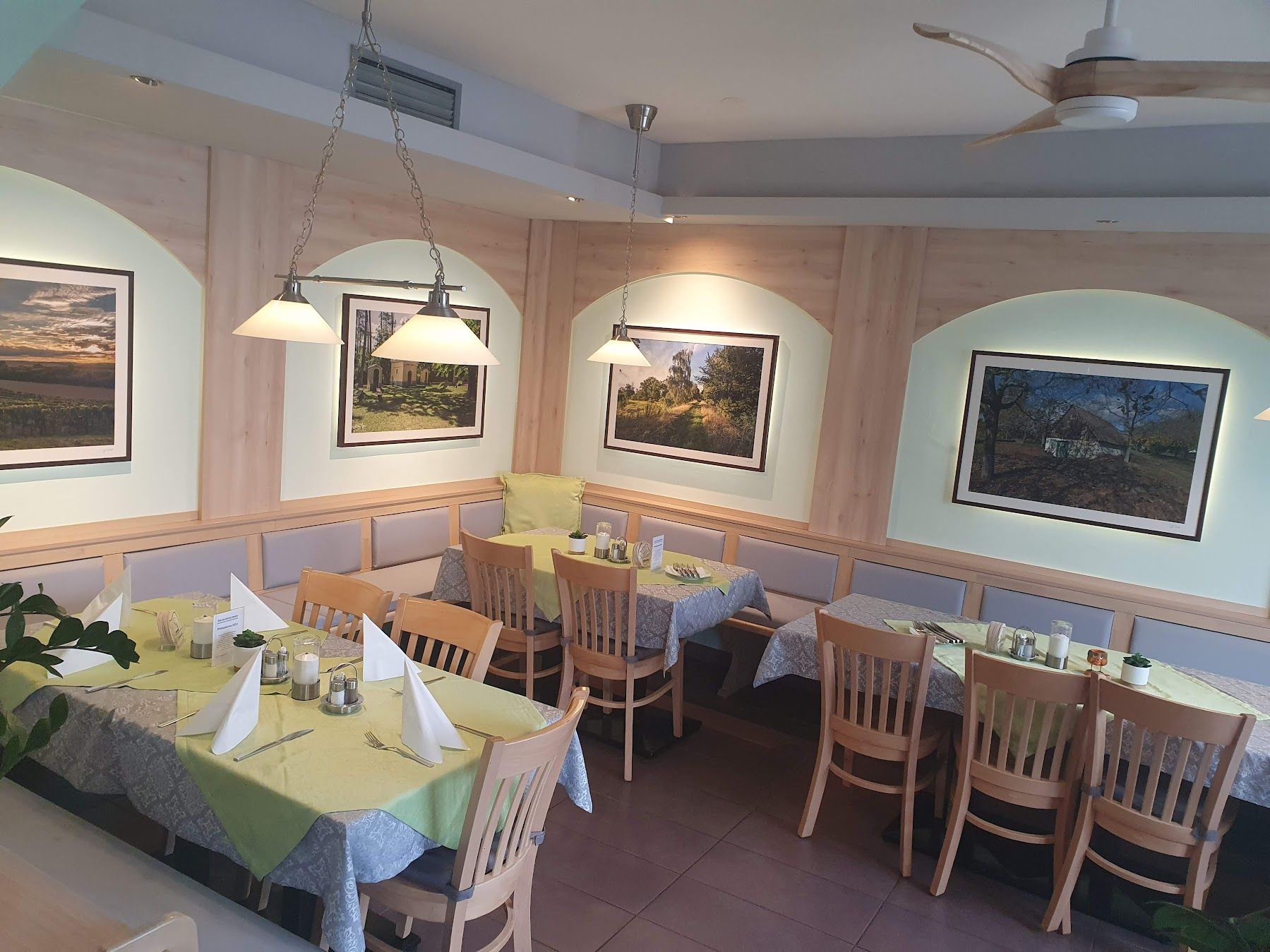 Interior view of a restaurant with wooden furniture and decorative pictures on the wall.
