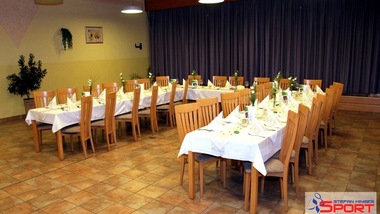 A festively laid table in a restaurant with wooden chairs and white tablecloths.