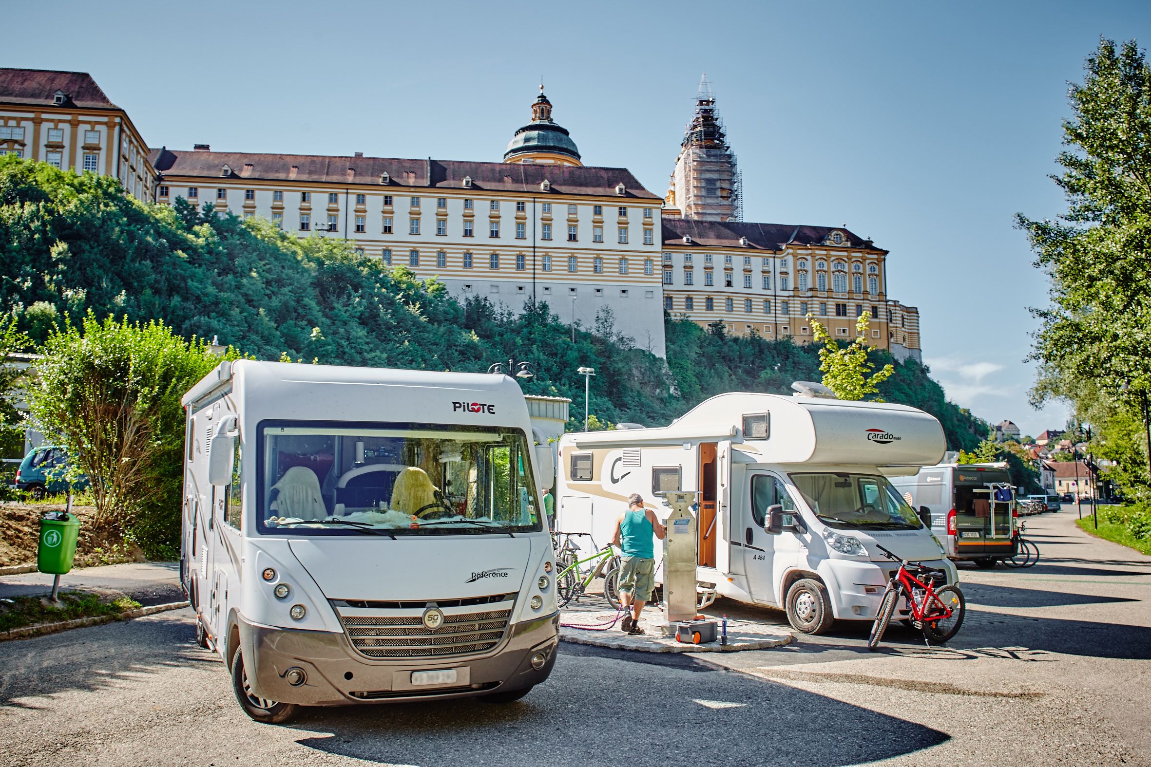 Motorhome parking area with motorhomes in front of Melk Abbey in Austria.
