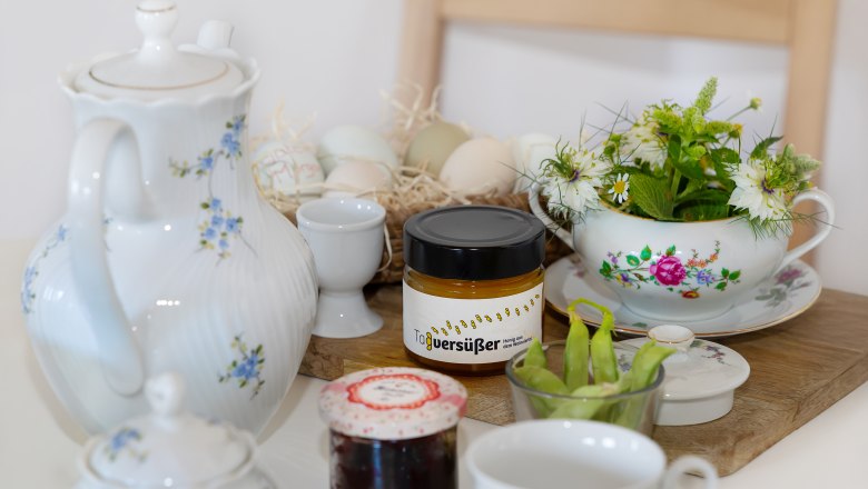Vacation cottage Weinmeyer, © Josef Schimmer Breakfast table with teapot, jar of honey, jam, eggs and flowers.