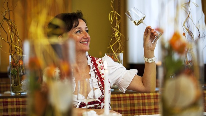 Schönauer Inn, © Lois Lammerhuber Woman in traditional dress holding a wine glass in a restaurant.