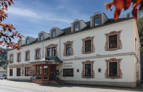 Historic building with decorative window frames and signs for hotel and restaurant.