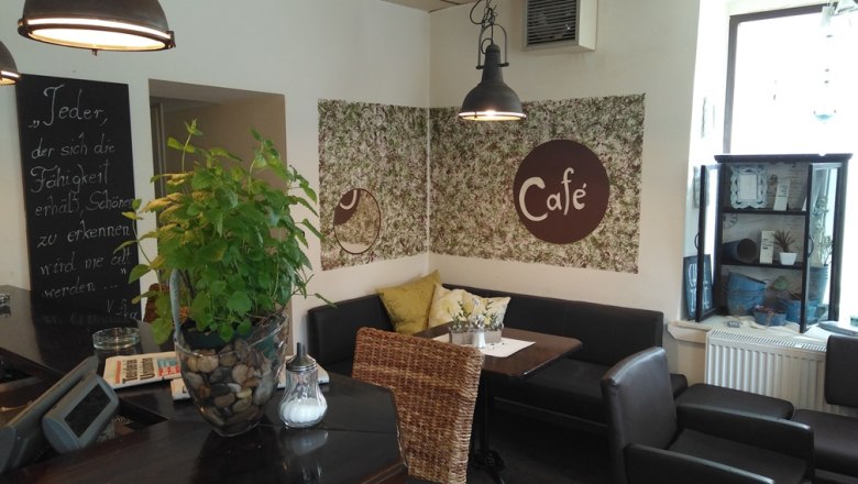 Cozy café with plants, seating and decorations.