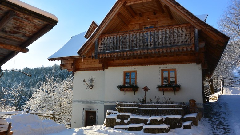 Traditional house with half-balcony and white fa&ccedil;ade, surrounded by snowy landscape.