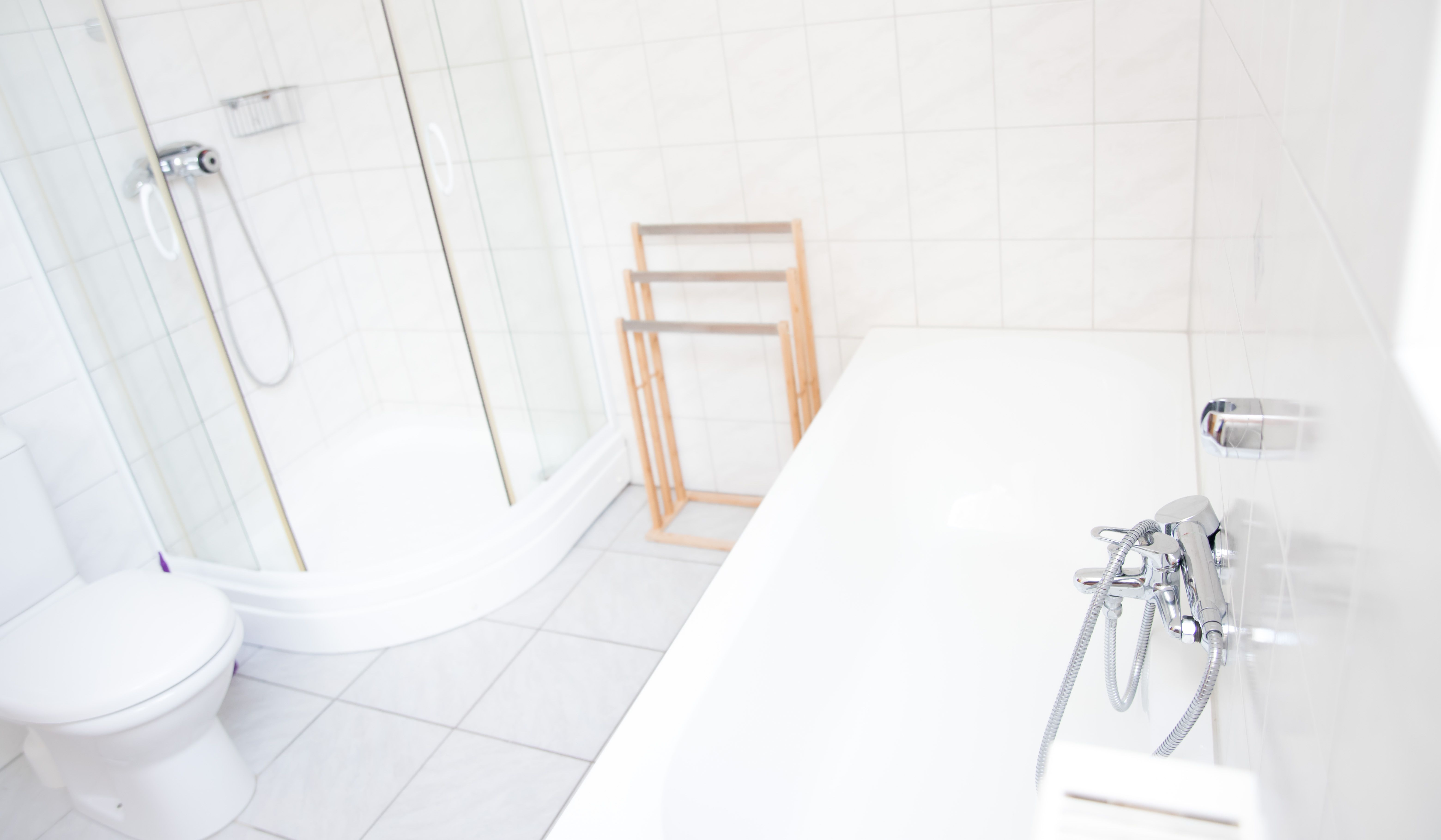 Bright bathroom with shower, bathtub and towel rail.