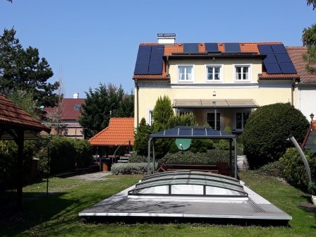 A house with solar panels and a covered pool in the garden.