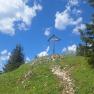 Summit cross on a hill with blue sky and clouds.