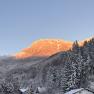 Snow-covered mountain landscape with orange illuminated summit at sunset.