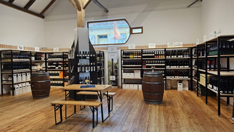 Interior view of a wine shop with wine racks and wooden tables.